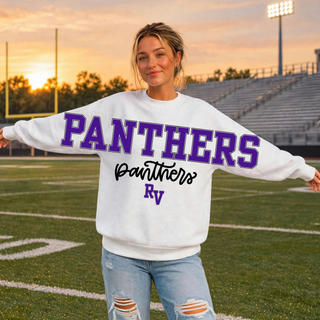 Woman wearing an oversized white Royal Valley Panthers crewneck sweatshirt with a stacked PANTHERS block letter, panthers script, and RV initial graphic on the front