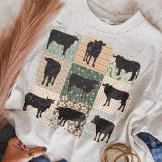 Close up of oatmeal t shirt with nine distressed black cattle silhouettes on vintage floral gingham and boho patchwork quilt squares with pampas grass