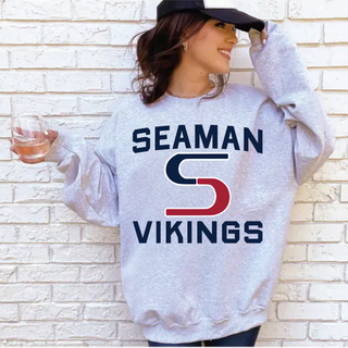 Athletic heather crewneck with Seaman Vikings rally S logo graphic, worn by a woman in a navy hat against a brick wall
