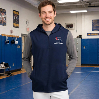 Smiling model in a wrestling room wearing a navy sleeveless hooded quarter-zip over a grey long sleeve with the S Wrestling logo on the left chest