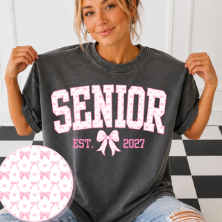 Pepper gray tee on a model with a circular close-up of the pink bow and heart pattern used in the SENIOR EST. 2027 design