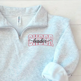 Ash Grey Quarter-Zip Pullover with CHEER leader spirit design on left chest. CHEER in red varsity outline with leader in black script. Flat lay on white wood