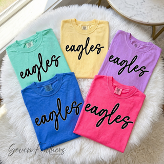 Folded pastel Comfort Colors tees with eagles script design in mint, yellow, lavender, pink, and blue
