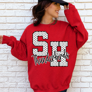 Woman in a red crewneck sweatshirt with white polka dot SH letters outlined in black and black Thunderbirds script
