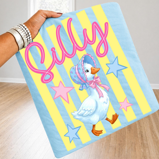 Hand holding blue yellow striped blanket with Silly pink script and vintage goose in bonnet design, infant adult