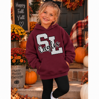 Girl in a maroon hoodie with white polka dot SL letters outlined in black and black Eagles script, standing on a fall porch with pumpkins