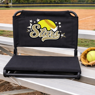 Black padded stadium seat with gold and yellow SL Stars softball logo featuring yellow softball gold script Stars text and white star burst DTF print on back displayed on aluminum bleachers with softball glove and yellow softball beside it