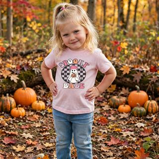 Toddler wearing pink spooky checkered babe top with retro ghost and checkered circle graphic