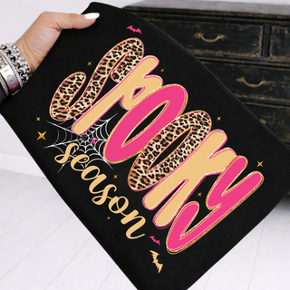 Black top with bold pink and gold Spooky Season leopard print lettering bats and spider web halloween design
