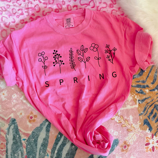 Neon pink tee with wildflower stems and SPRING text graphic flat lay front view
