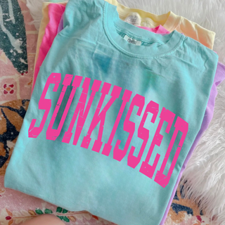 Stacked Comfort Colors tees in chalky mint, neon pink, butter, and orchid with Sunkissed distressed varsity graphic

