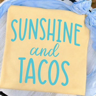 Butter yellow tee laid flat showing SUNSHINE and TACOS graphic in turquoise script and block lettering
