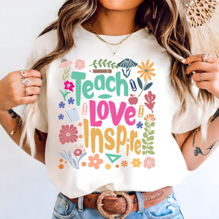 Model wearing ivory Teach Love Inspire Wildflower graphic top with colorful floral and school supply design
