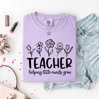 Violet Comfort Colors tee folded flat with TEACHER helping little minds grow floral line art design
