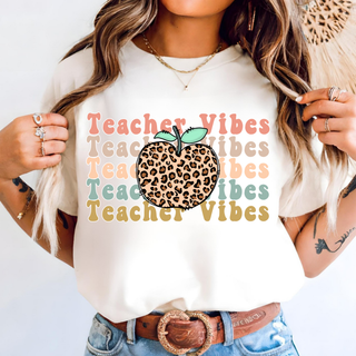 White tee with retro stacked Teacher Vibes text and leopard apple, styled with jeans and belt