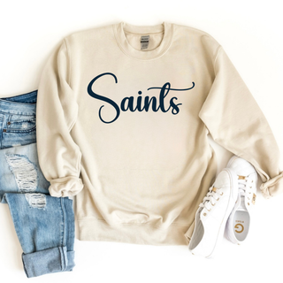 Ivory crewneck sweatshirt with the Topeka Saints signature script graphic styled with jeans and white shoes