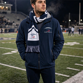 Man wearing Topeka Seaman Vikings football S logo stadium scarf in navy and white on football field
