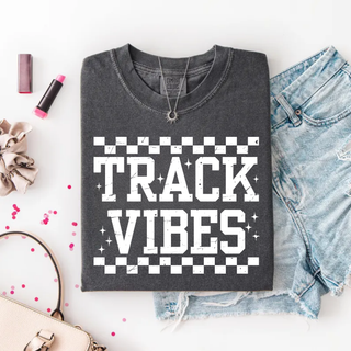 Folded pepper tee laid flat with TRACK VIBES bold checkered varsity graphic and sparkle star accents
