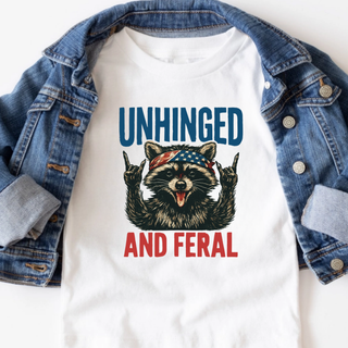 White tee with Unhinged and Feral raccoon wearing American flag bandana design styled with denim jacket