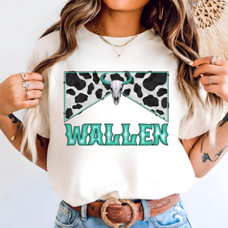 Model wearing ivory Wallen Bull Skull Country graphic top with teal Wallen text bull skull and cow print design
