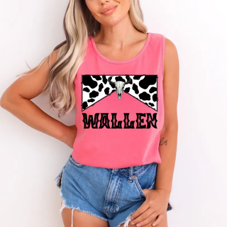 woman wearing bright pink garment dyed cotton tank top with black and white cow print bow, longhorn skull, and black wallen text paired with denim shorts

