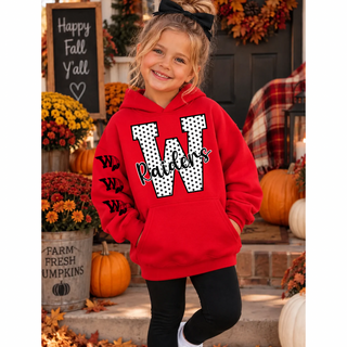 Girl in a red hoodie with a white polka dot letter W outlined in black and black Raiders script on the front, with three black W logos with feather accents down the sleeve, standing on a fall porch with pumpkins
