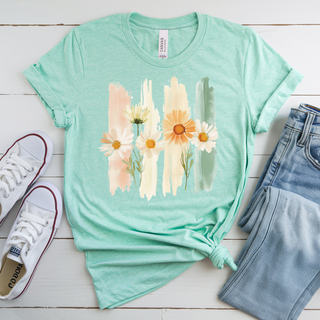 Heather Prism Mint Bella Canvas top with a watercolor daisy and brushstroke graphic in peach cream and sage laid flat with white sneakers and denim