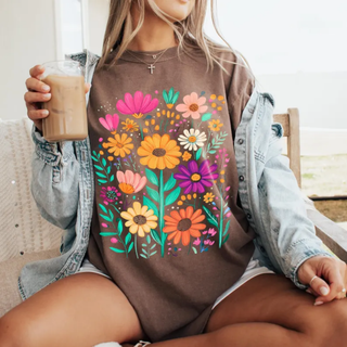 Woman in espresso graphic tee with colorful wildflower bouquet print holding iced coffee wearing denim jacket
