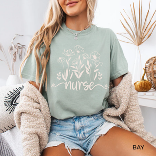 Woman in bay Comfort Colors tee with white wildflower and nurse script graphic
