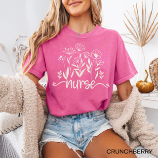 Woman in crunchberry Comfort Colors tee with white wildflower bouquet and nurse script graphic
