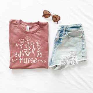 Folded heather mauve Bella Canvas Wildflower Nurse Graphic Tee with delicate wildflower bouquet and nurse script design