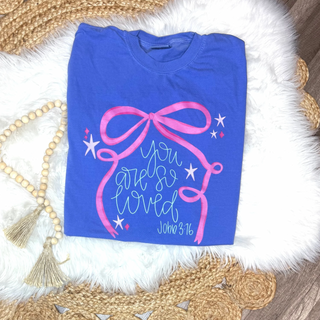 Flo blue Comfort Colors tee folded flat with pink bow and you are so loved John 3:16 script graphic
